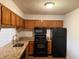 Functional kitchen with granite countertops, wooden cabinets, black appliances, and wood floors at 323 Seasons Pkwy, Norcross, GA 30093
