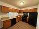 Cozy kitchen with granite countertops, wooden cabinets, black appliances, and wood flooring at 323 Seasons Pkwy, Norcross, GA 30093