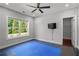 Bright workout room featuring a blue padded workout area, television, and a leafy view from the large window at 3024 Eamont Ter, Atlanta, GA 30328
