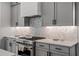 Stylish kitchen showcasing gray cabinetry, modern appliances, quartz countertop, and elegant backsplash detailing at 3024 Eamont Ter, Atlanta, GA 30328