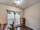A home office features a wood desk, a black office chair, a window with blinds and curtains, and dark wood floors at 59 Sentry Rdg, Dallas, GA 30157