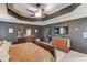 Main bedroom featuring neutral decor, tray ceiling, fan, and flat screen TV at 657 Swans Landing Dr, Dacula, GA 30019
