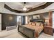 Main bedroom features neutral decor, tray ceiling, fan, and ensuite bathroom at 657 Swans Landing Dr, Dacula, GA 30019