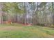 Backyard with a playground in a fenced in area surrounded by mature trees at 657 Swans Landing Dr, Dacula, GA 30019