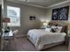 Neutral bedroom showcasing a queen-size bed, carpet floors, desk, and decorative pillows and wall art at 1054 Georgian Point Dr, Lawrenceville, GA 30045