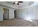 Large bedroom featuring neutral carpeting, tray ceiling with ceiling fan, and two entry doors at 3088 Mount Tabor Church Rd, Dallas, GA 30157