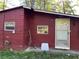 Close view of a home exterior with dark red siding and an aluminum door at 520 Pine Dr, Pine Lake, GA 30072