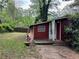 Exterior view of a red home featuring a small porch and front yard at 520 Pine Dr, Pine Lake, GA 30072