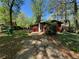 View of the home's exterior and unkempt front yard with green waste can at 520 Pine Dr, Pine Lake, GA 30072