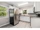 The well-lit kitchen features white cabinets, stainless steel appliances, and modern flooring at 5844 Earlwane Dr, Lithonia, GA 30058