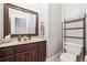 A bathroom with a granite countertop, framed mirror, and a traditional toilet and shelving unit at 255 Helens Manor Dr, Lawrenceville, GA 30045