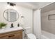 Updated bathroom with a wood vanity, modern fixtures, round mirror, and a shower-tub combo at 1690 Cotswold Ne Dr, Brookhaven, GA 30319