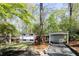Mid-century modern home with a carport, mature trees, manicured lawn, and stone walkway at 1690 Cotswold Ne Dr, Brookhaven, GA 30319