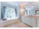 Bright bathroom with window seat and storage, large mirror, and white cabinets with marble countertops at 2167 W Wesley Nw Rd, Atlanta, GA 30327