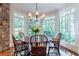 Sun-drenched dining area boasts a round wood table, chandelier lighting, and large windows with lush green views at 2167 W Wesley Nw Rd, Atlanta, GA 30327