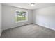 This bedroom has neutral carpet, white walls, and a window overlooking the front yard at 10924 Hondal Ct, Hampton, GA 30228
