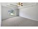 Main bedroom featuring tray ceiling, ceiling fan, neutral carpet, and a large window at 10924 Hondal Ct, Hampton, GA 30228