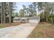 Ranch home with a charming front porch and attached garage, complemented by a long driveway and lush trees at 2000 Hill Rd, Marietta, GA 30062