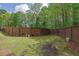A backyard with grass and a privacy fence surrounded by lush trees at 984 Redwood Dr, Norcross, GA 30093