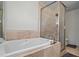Bathroom featuring large soaking tub, glass enclosed shower with tile surround and showerhead at 2645 Sandstone Dr, Lawrenceville, GA 30043