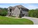 Side view of two-story gray brick home with an attached garage, a well-manicured lawn, and mature trees at 3206 Letha Woods Dr, Conyers, GA 30094