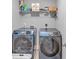 Laundry room with two front-loading blue washing machines and overhead shelving at 3206 Letha Woods Dr, Conyers, GA 30094