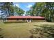 Single story brick house with red roof and green yard surrounded by tall pine trees at 50 Silver Lake Dr, Mansfield, GA 30055