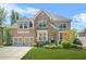 Charming two-story brick and stone home with a well-manicured lawn and a two-car garage at 5895 Springbox Dr, Suwanee, GA 30024