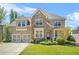 Charming two-story brick and stone home with a well-manicured lawn and a two-car garage at 5895 Springbox Dr, Suwanee, GA 30024