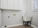 This laundry room has white cabinets, a utility sink, and wood look flooring at 175 Oak Manor, Fayetteville, GA 30214