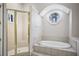 Bright bathroom with a shower and oval window above a soaking tub at 175 Oak Manor, Fayetteville, GA 30214