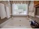 Bathroom featuring a large soaking tub under a window with natural light and neatly hung towels at 84 Ledbetter Rd, Villa Rica, GA 30180