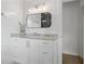 Contemporary bathroom featuring white cabinetry, marble countertop, modern lighting, and ample storage at 9315 Prestwick Club Dr, Johns Creek, GA 30097