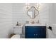 Elegant powder room features shiplap walls, a cloverleaf mirror, and navy blue vanity cabinet at 9315 Prestwick Club Dr, Johns Creek, GA 30097