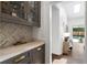 Butlers pantry featuring quartz countertops, glass front cabinets, and marble pattern backsplash at 9315 Prestwick Club Dr, Johns Creek, GA 30097