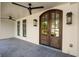 Inviting front porch featuring ceiling fans and a beautiful arched wood entry door at 9315 Prestwick Club Dr, Johns Creek, GA 30097