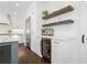 Elegant kitchen boasts white cabinetry, marble countertops, floating shelves, and a built-in beverage cooler at 9315 Prestwick Club Dr, Johns Creek, GA 30097