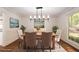 Staged dining room with a wood table, seating for six, a modern light fixture, and a large window at 6141 Windsong Way, Smoke Rise, GA 30087