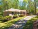 Brick home with a long driveway, showcasing a columned porch, well-maintained lawn, and lush surrounding greenery at 6141 Windsong Way, Smoke Rise, GA 30087