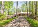 Long driveway leads to a traditional brick home with a columned porch, surrounded by lush greenery and blooming flowers at 6141 Windsong Way, Smoke Rise, GA 30087