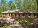 Inviting brick home with a columned front porch and well-manicured lawn surrounded by lush greenery at 6141 Windsong Way, Smoke Rise, GA 30087