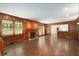 Spacious living room boasts a fireplace, wood paneling, and abundant natural light from large windows at 6141 Windsong Way, Smoke Rise, GA 30087