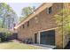 Back of a brick home featuring a black garage door, surrounded by trees and greenery at 6141 Windsong Way, Smoke Rise, GA 30087