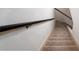A carpeted staircase with a black handrail leads to the next level at 6141 Windsong Way, Smoke Rise, GA 30087
