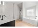 Well lit bathroom with double sinks, quartz countertops, and decorative window above the tub at 327 Morning Frost, Canton, GA 30114