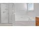 Bright bathroom showcasing a glass-enclosed shower and a luxurious soaking tub with tile surround at 3447 Dogwood Pass, Lithonia, GA 30038