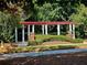 Beautiful pergola with red beams and white pillars surrounded by lush landscaping at 3447 Dogwood Pass, Lithonia, GA 30038