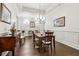 Elegant dining room with dark wood floors, wainscoting, and modern chandelier lighting at 1227 Magnolia Path Way, Sugar Hill, GA 30518