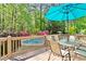 Scenic deck featuring a dining table with chairs, a partial view of the pool, and surrounded by lush trees at 1315 Pembridge Nw Way, Kennesaw, GA 30152