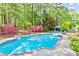 Sparkling pool surrounded by vibrant azaleas, mature trees, and a cozy seating area for outdoor relaxation at 1315 Pembridge Nw Way, Kennesaw, GA 30152